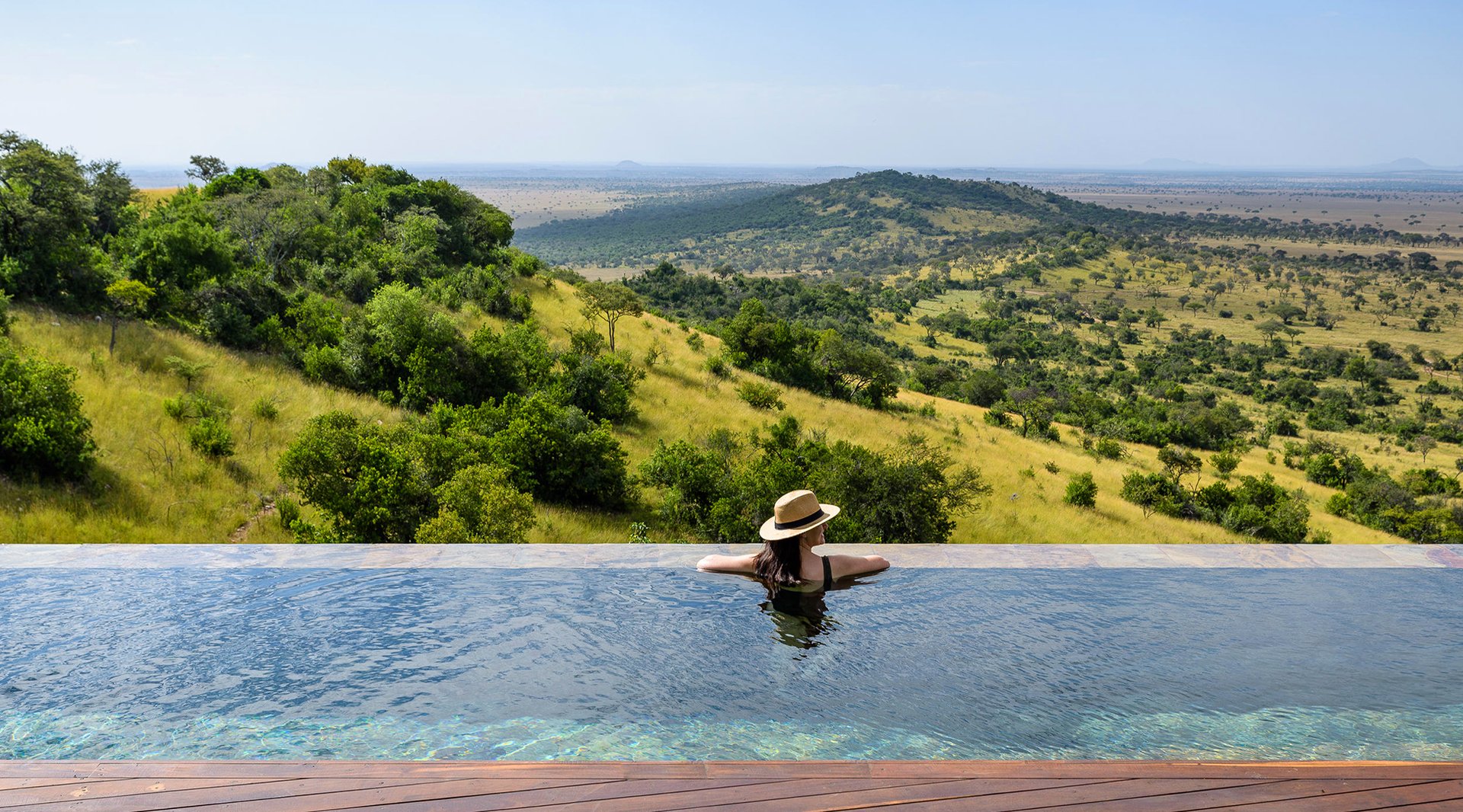 Frau im Pool überblickt Landschaft von Grumeti