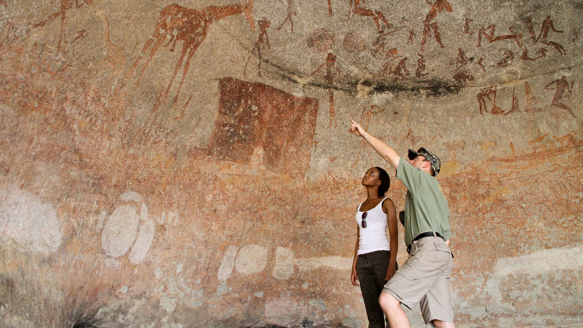 Eine Frau und ein Mann betrachten die Felsenzeichnungen im Matobo Nationalpark